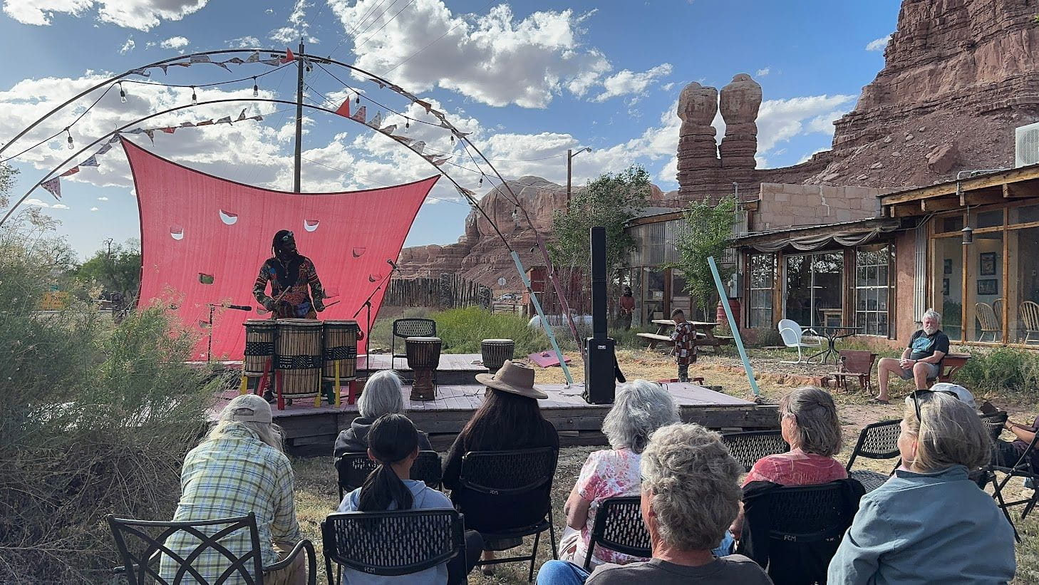 Outdoor performance with a drummer and audience in a desert setting.