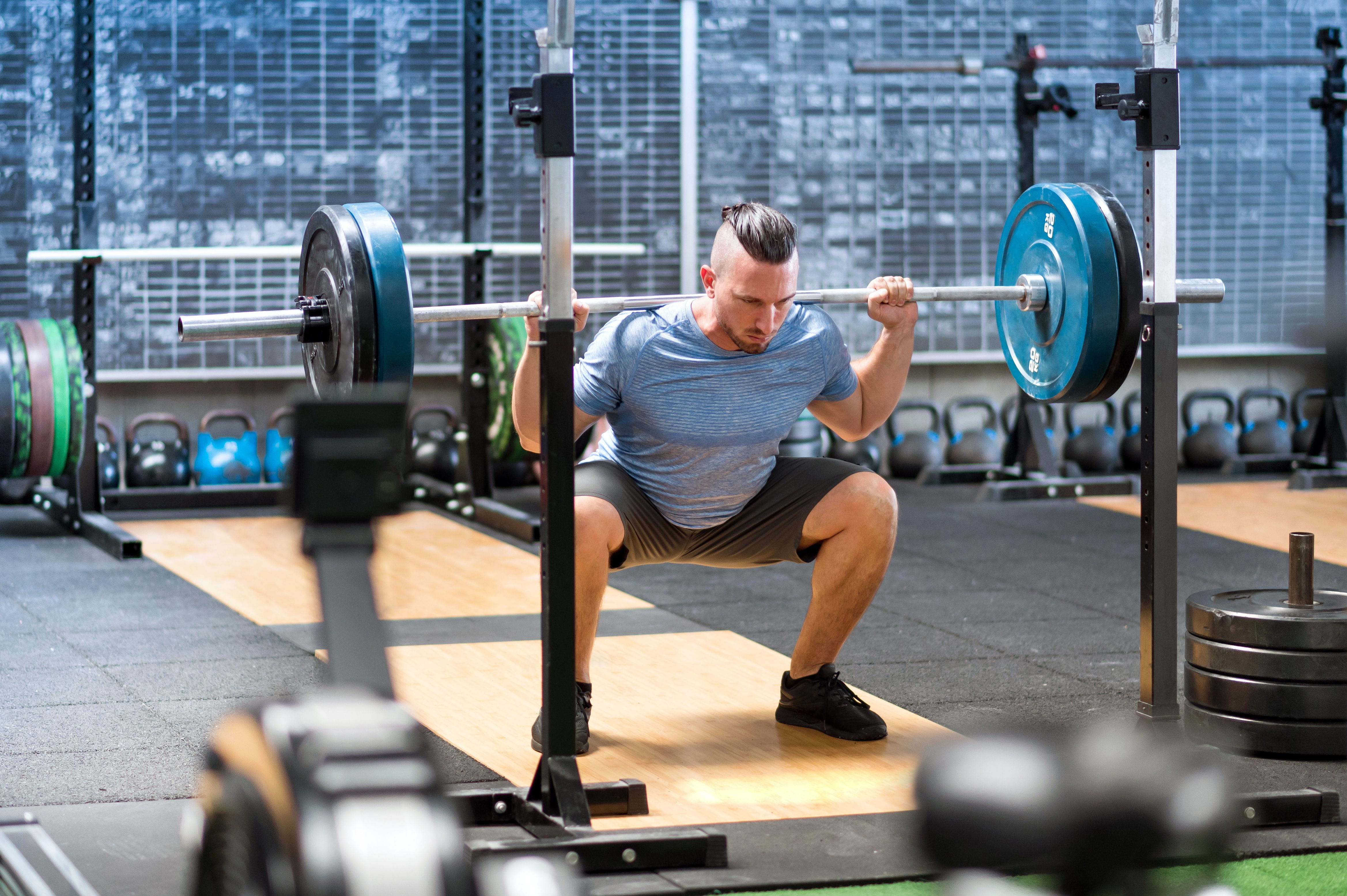  muž ktorý cvičí drep s činkou