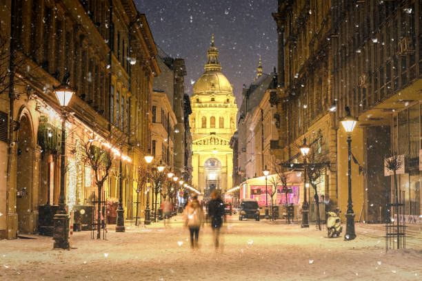 Illuminated cityscape of Zrinyi Street in Budapest with St Stephen's Basilica in a snowy winter landscape at dusk Budapest cityscape with Zrinyi Street and St Stephen's Basilica at dusk Hungary TOURIST PLACES stock pictures, royalty-free photos & images