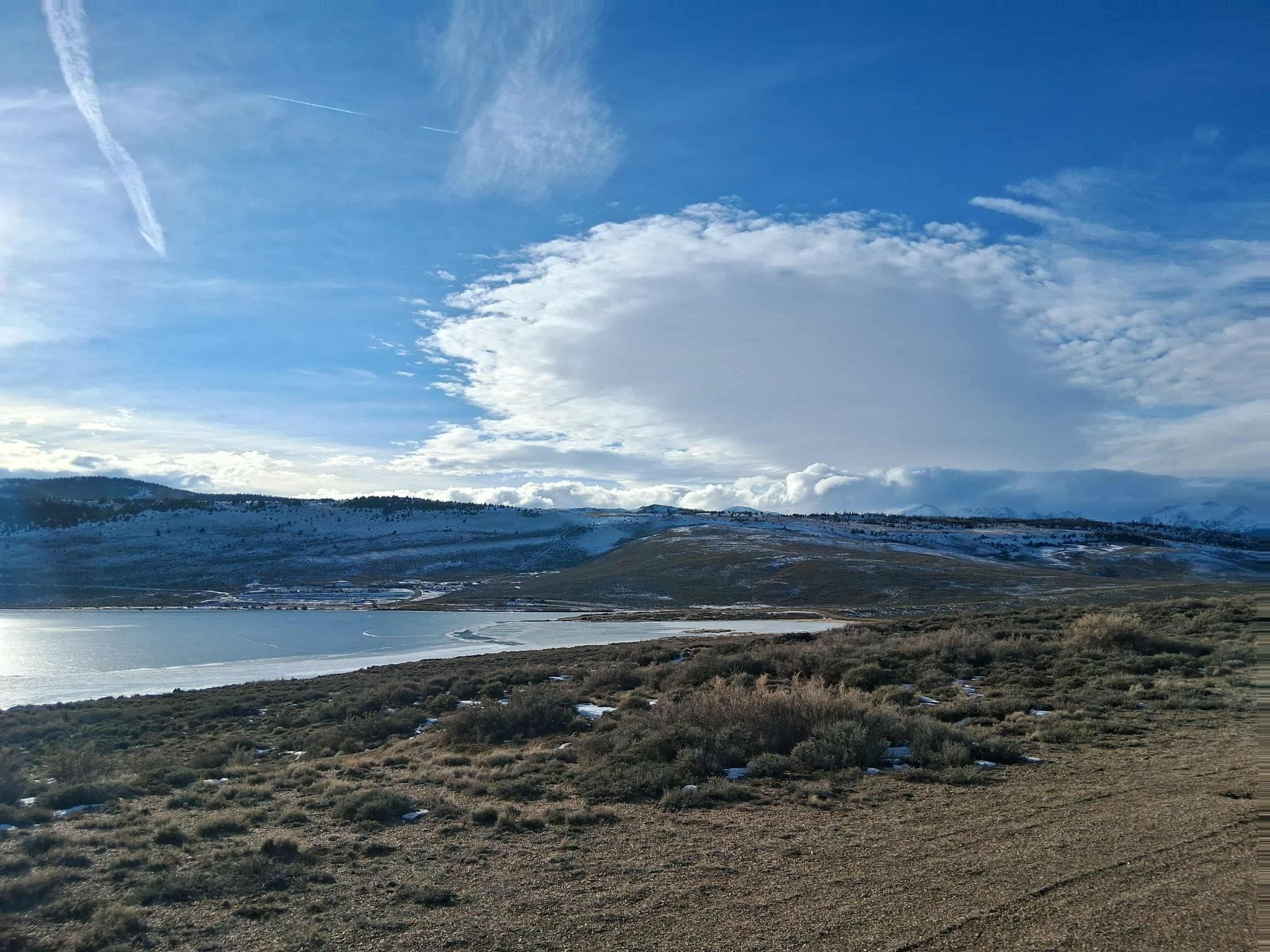 View of Lake John from the shore with the Park Range and clouds in the background.
