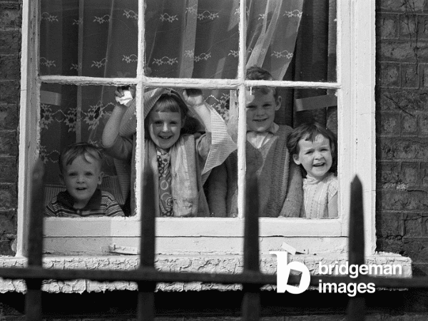 Fotografie von Joseph McKenzie, die Kinder zeigt, die aus einem Fenster rausgucken