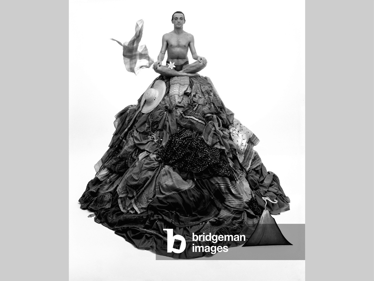 cross-legged man on clothes-pile