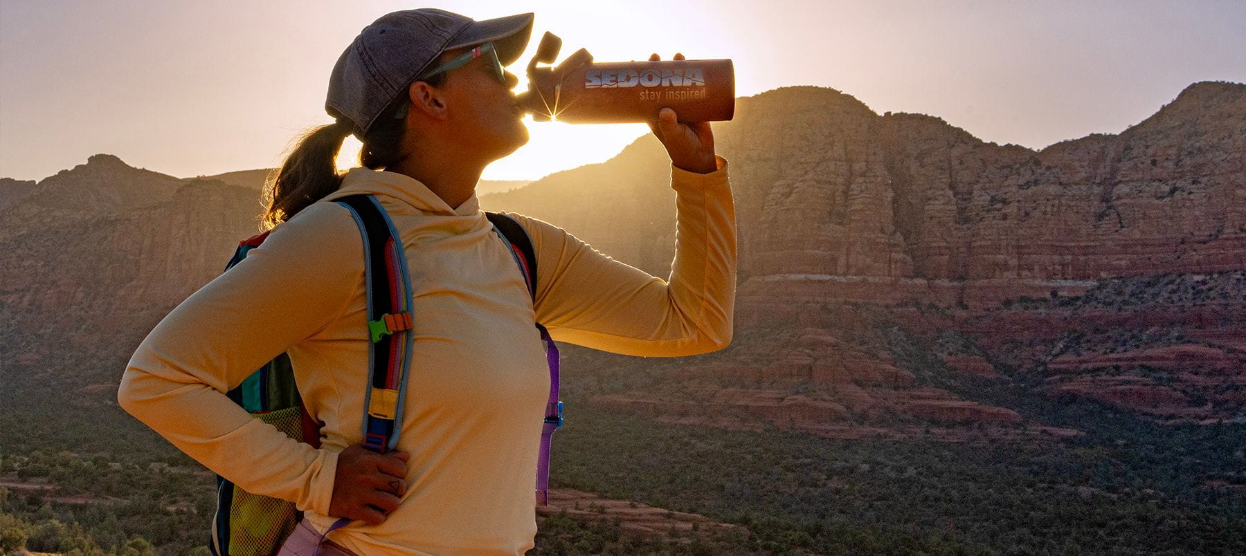 Woman drinking from her water bottle while hiking.