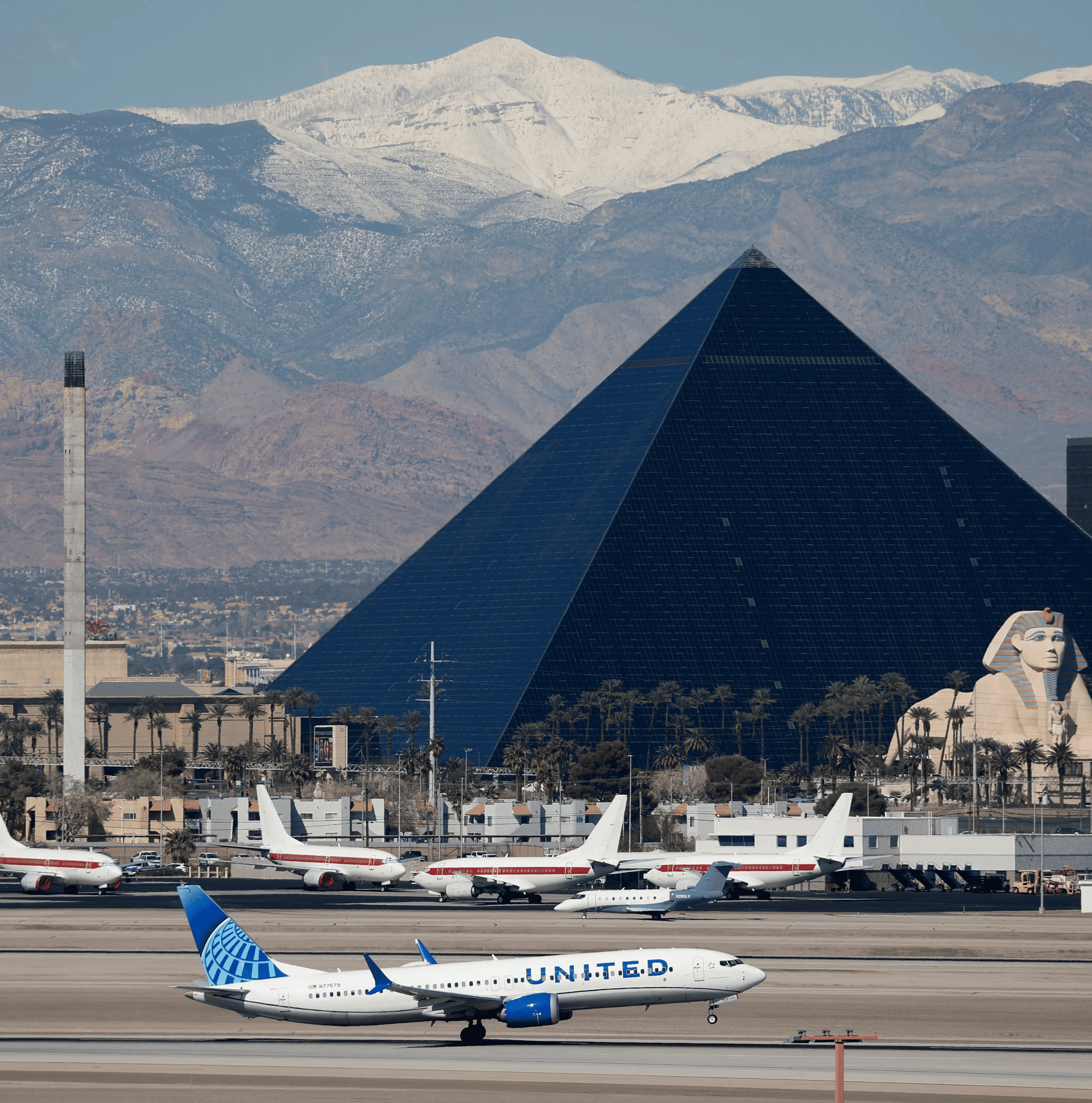 White airplanes on the ground in font of a giant black pyramid building in Las Vegas