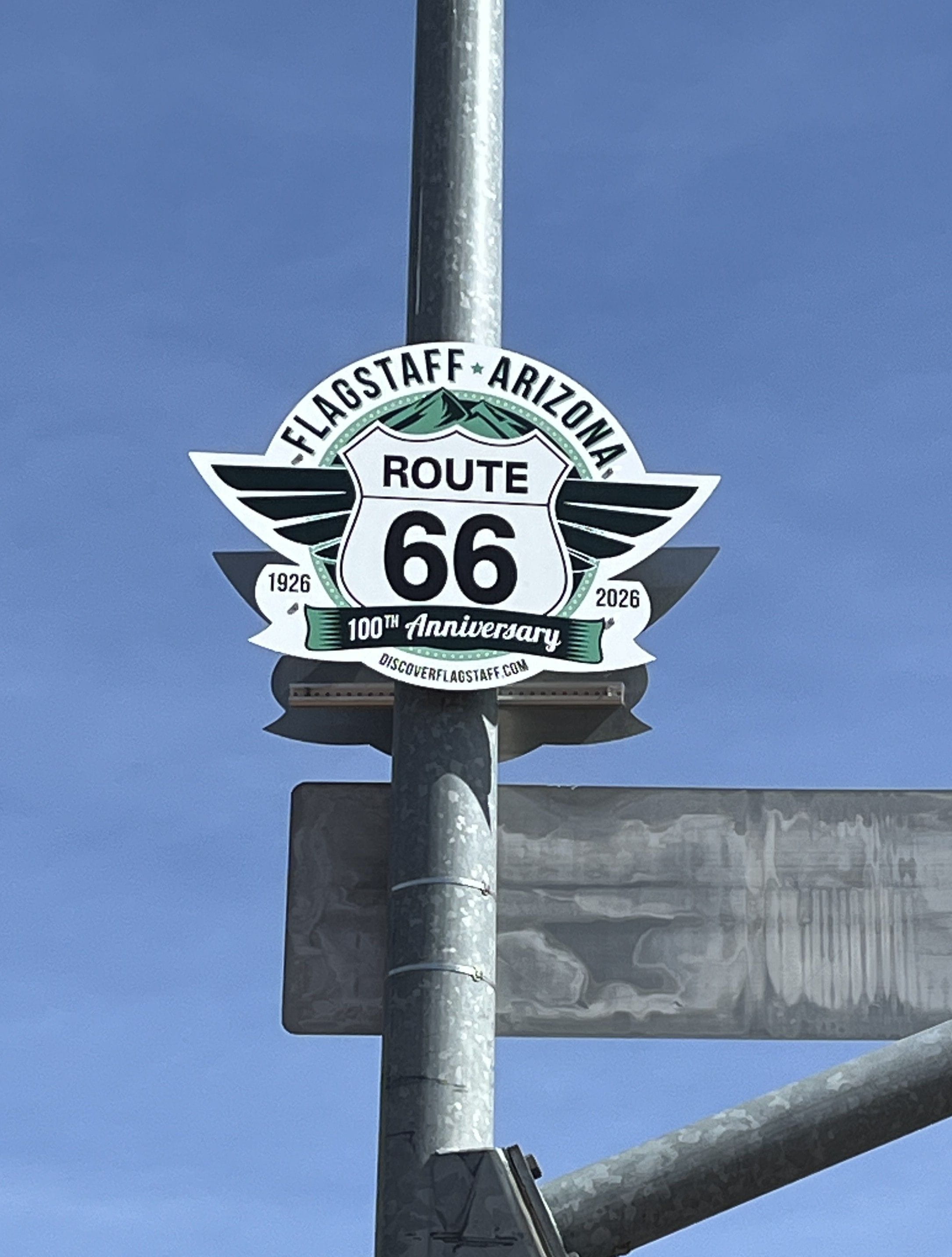 Route 66 Centennial commemorative sign on a street pole in Flagstaff.