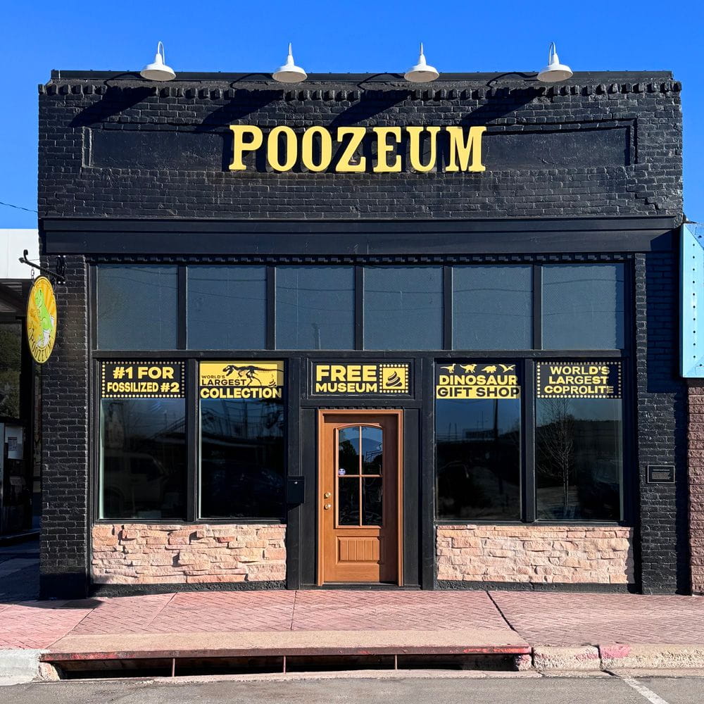 Black brick storefront with yellow letters of the Poozeum in Williams, Arizona.
