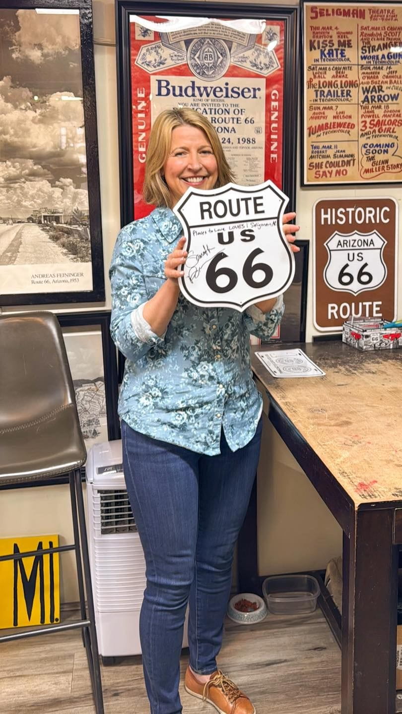A woman holding a metal route 66 shield.