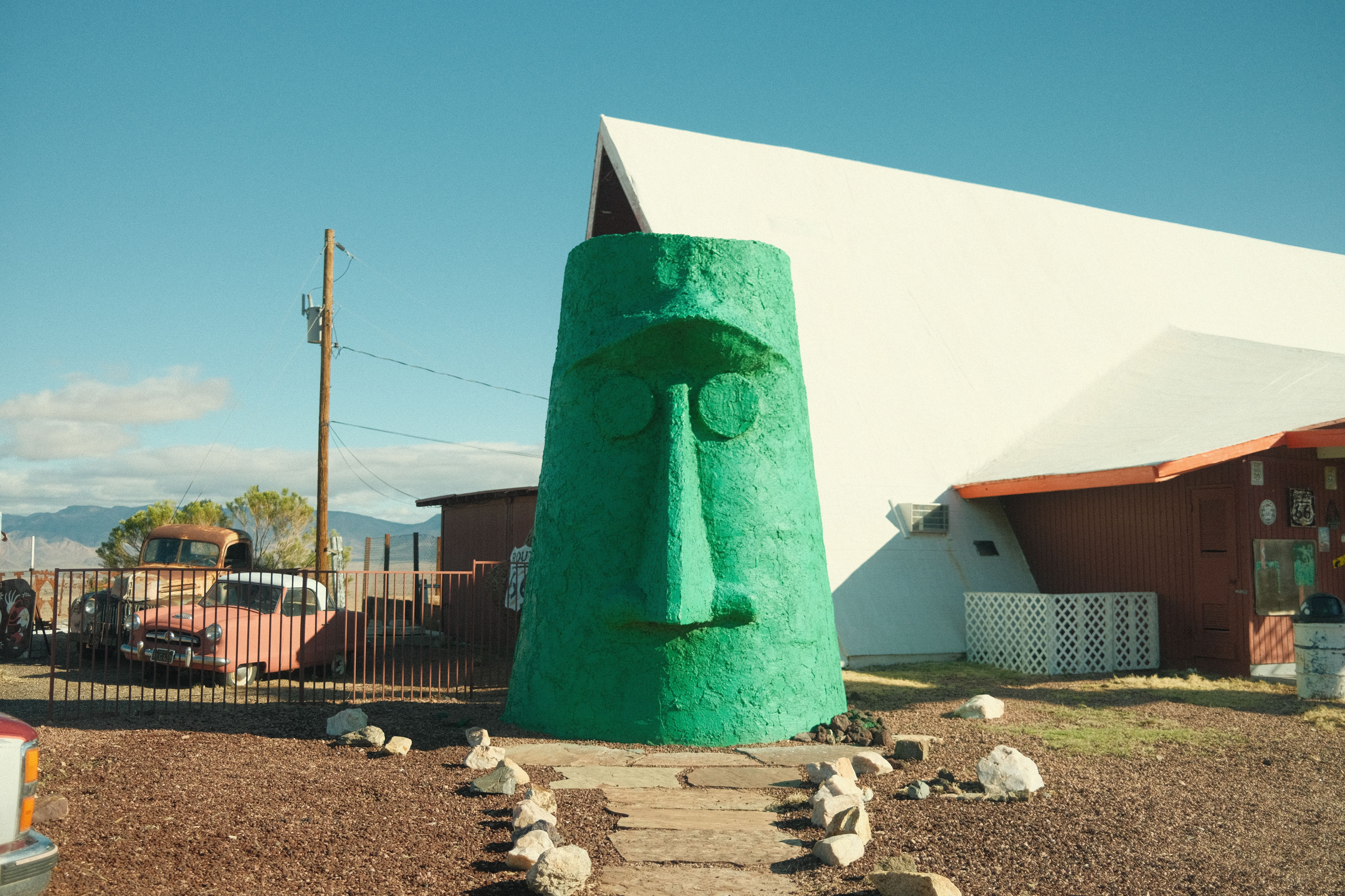 Large green tiki head statue with rock path leading up to it